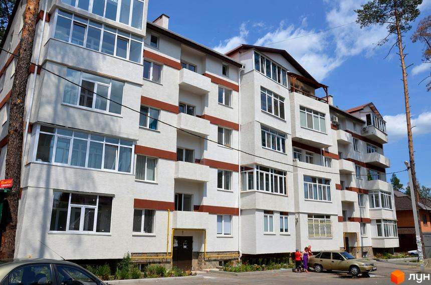 Новобудова на вулиці Університетська, 2ю. Фасад будинку білий з коричневими горизонтальними смугами, багато вікон та балконів. Поруч дерева та прибудинкова територія.