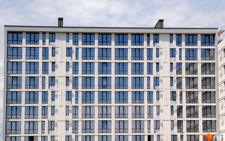 Фасад новобудови ЖК Kniahynyn-Center з численними вікнами та балконами. Будівельний проєкт з сучасною архітектурою.