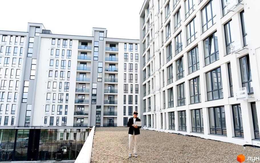 Житловий комплекс Kniahynyn-Center - це сучасна архітектура з великою кількістю вікон та балконів, розташований на даху з гравійним покриттям.