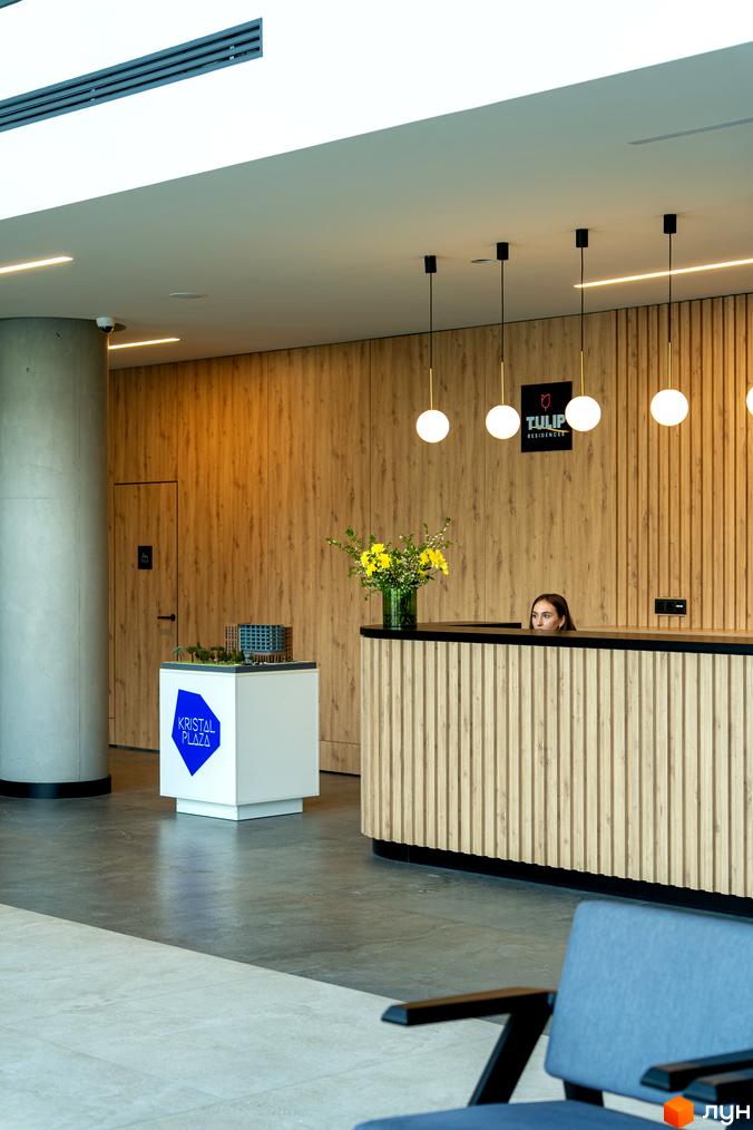 Рецепція апарт-комплексу Kristal Plaza з моделлю будівлі та квітковою композицією. Зображення інтер'єру новобудови.