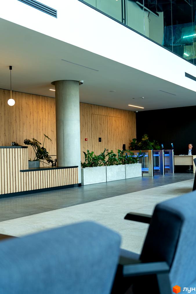 Апарт-комплекс Kristal Plaza: просторий хол з рецепцією, турнікетами та зонами відпочинку. Сучасний дизайн інтер'єру з дерев'яними панелями та зеленню.