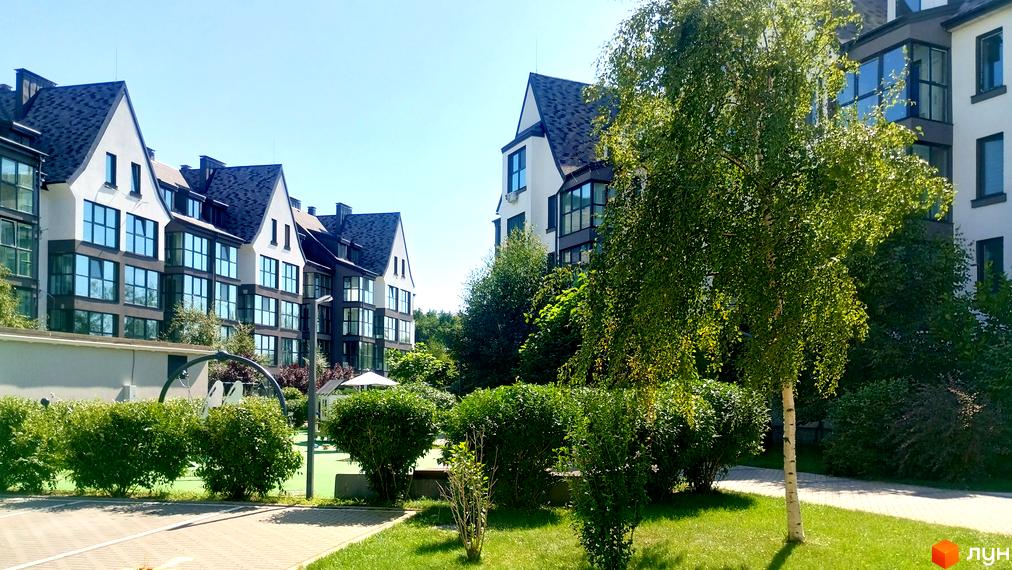 Житловий комплекс Desna Park Residence з білими фасадами та темними дахами, зеленою прибудинковою територією та дитячим майданчиком.