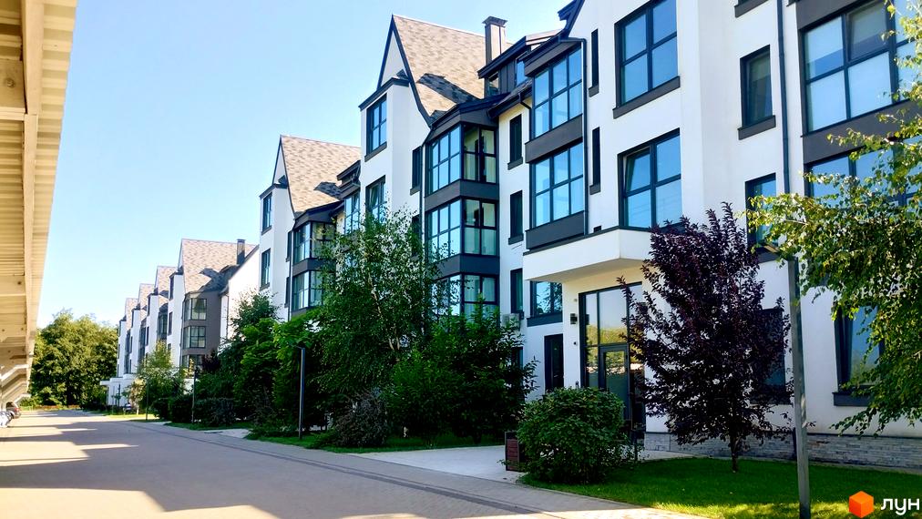 Будинок житлового комплексу Desna Park Residence з великими вікнами та сірими елементами фасаду, оточений зеленню та деревами.