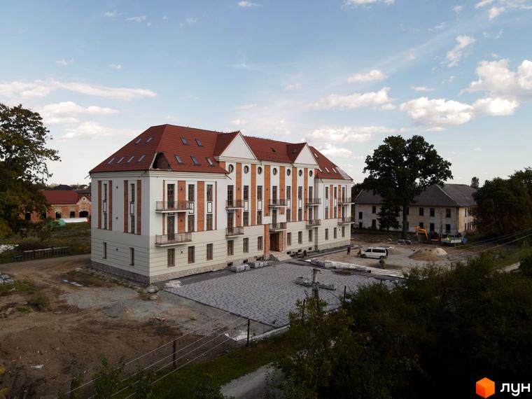 Житловий комплекс Австрійський - цегляний будинок з червоним дахом та прибудинкова територія з будівельними роботами.