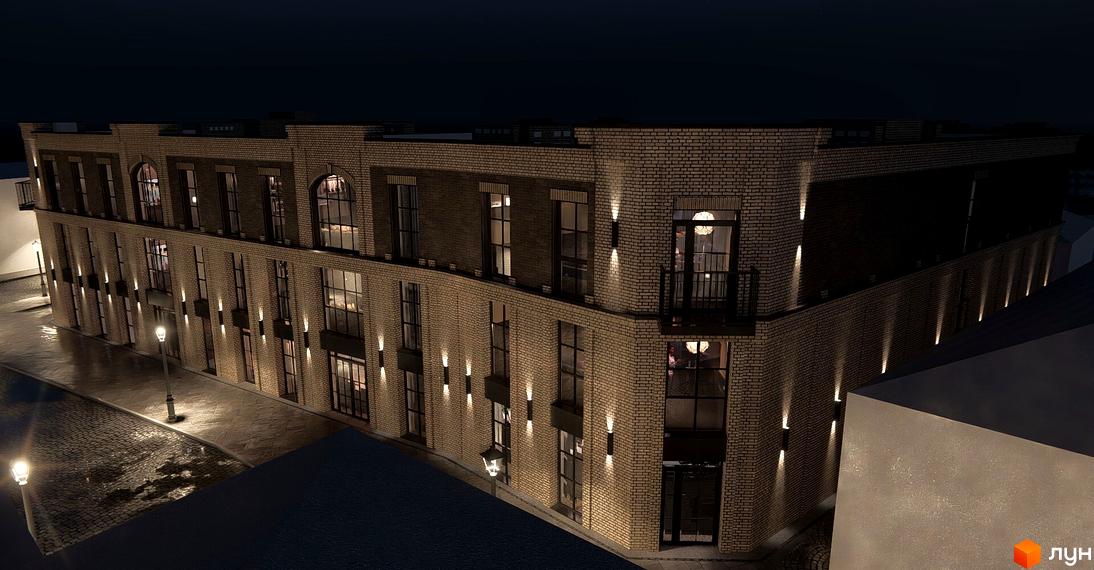 Зовнішній вигляд новобудови ЖК Замковий з цегляним фасадом та підсвічуванням вночі. Поруч брукована вулиця та ліхтарні стовпи.