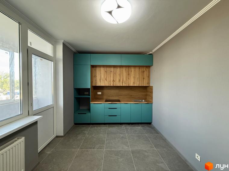 Сучасна кухня в новобудові ЖК Центр з бірюзовими фасадами та дерев'яними елементами. Великі вікна забезпечують багато природного світла.