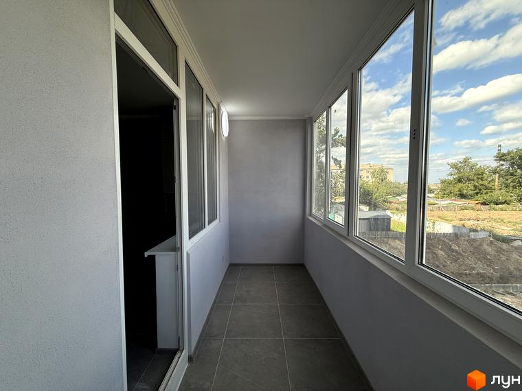 Балкон з панорамними вікнами в ЖК Центр. З вікон відкривається вид на будівлі та зелені насадження.