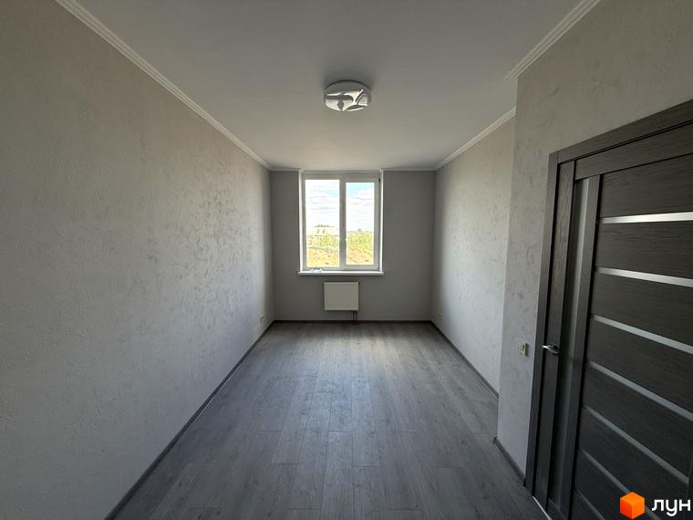 Житловий комплекс Центр: порожня кімната з великим вікном та дверима. Вікно виходить на зелену територію.