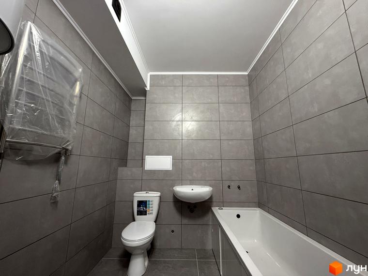 Сучасна ванна кімната з плиткою сірого кольору, білою ванною, унітазом та раковиною. ЖК Центр - ваш новий дім.