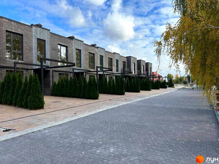 Таунхауси Eastville: фасади з цегли та бетону, зелені туї та вимощена бруківкою доріжка. Зовнішній вигляд новобудови та прибудинкової території.