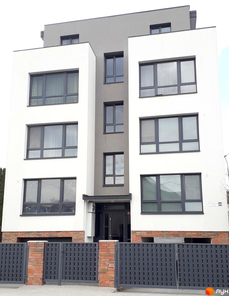Фасад будинку за адресою вул. Назарія Яремчука, 42, з великими вікнами та сірим парканом. Зовнішній вигляд новобудови.