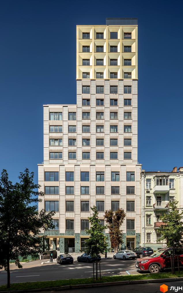 Фасад житлового комплексу Resident Concept House з сірими та золотими елементами, вікнами та прибудинковою територією з деревами та автомобілями.