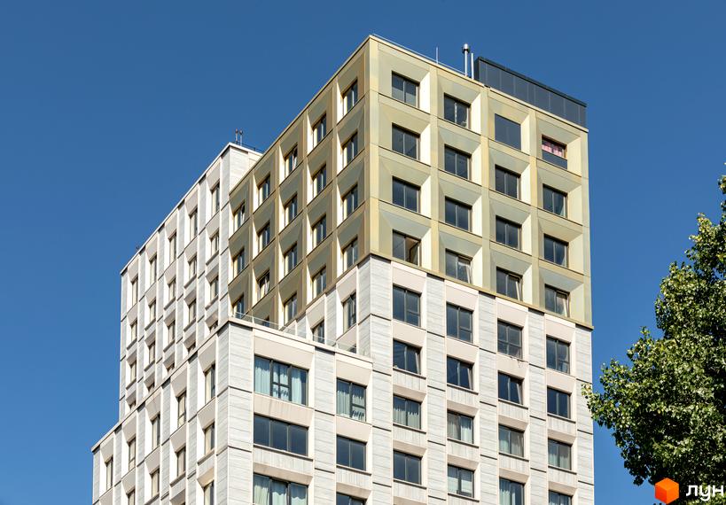 Зовнішній вигляд новобудови Resident Concept House з білими та золотистими фасадами та великою кількістю вікон на фоні блакитного неба.