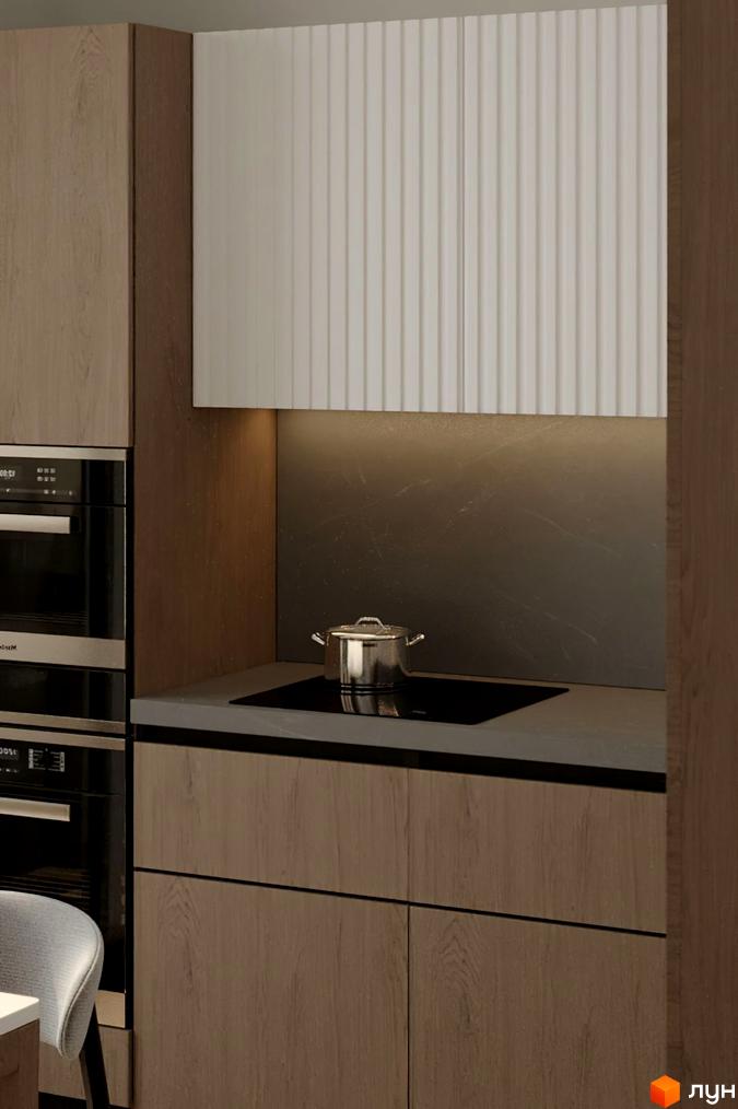 Сучасна кухня з дерев'яними фасадами та білою ребристою панеллю над робочою зоною. На плиті стоїть металевий каструля.