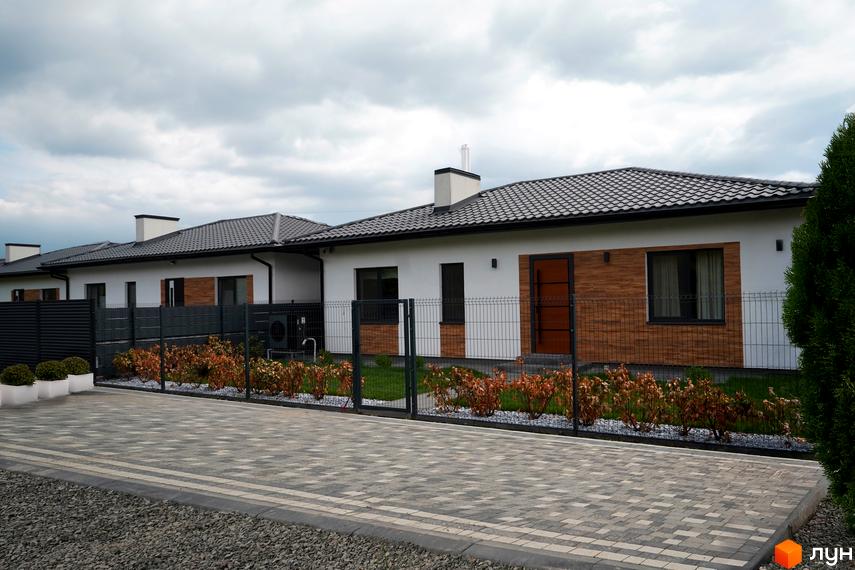 Котеджне містечко КМ MATRIX. Сучасні будинки з білою штукатуркою та дерев'яними елементами фасаду, огороджені парканом, з доглянутою прибудинковою територією.