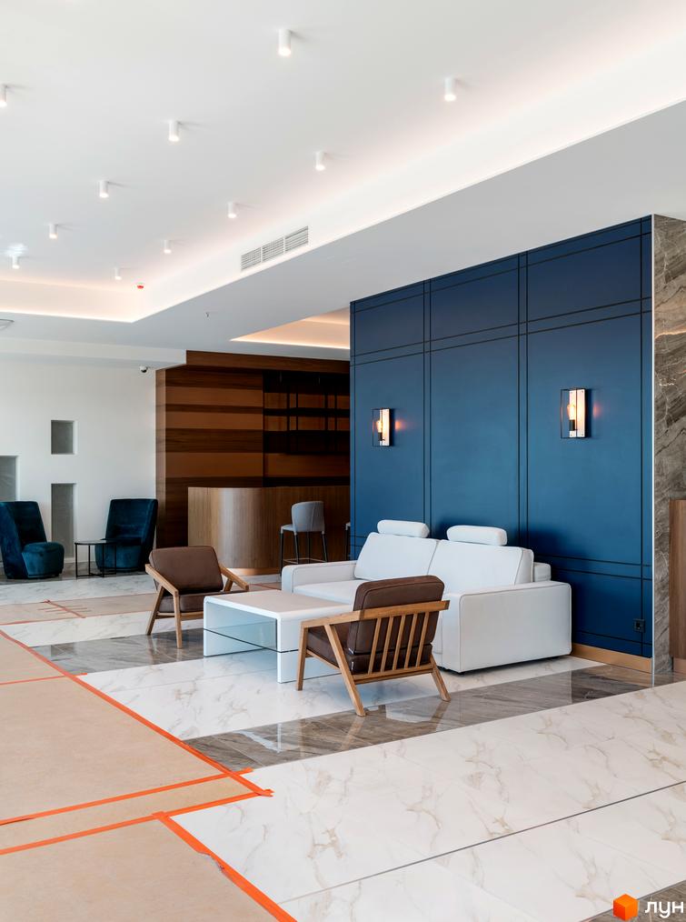 Інтер'єр лобі житлового комплексу Edelweiss House з диванами, кріслами та журнальними столиками. Сучасний дизайн зони відпочинку.