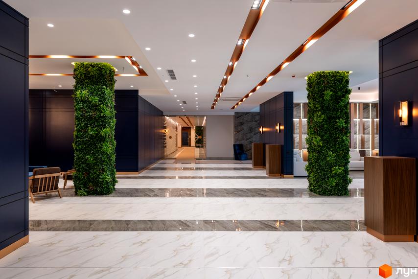 Інтер'єр холу житлового комплексу Edelweiss House з вертикальним озелененням та мармуровою підлогою. Сучасний дизайн простору для комфортного проживання.