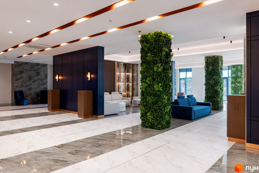 Інтер'єр лобі житлового комплексу Edelweiss House з вертикальним озелененням та зоною відпочинку. Сучасний дизайн та комфортні меблі створюють затишну атмосферу.