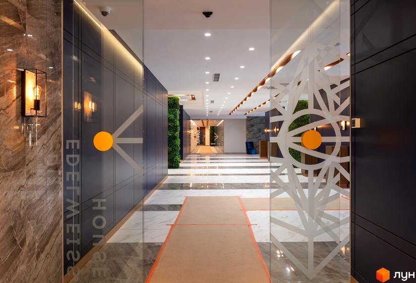 Вхідна група житлового комплексу Edelweiss House з вертикальним озелененням та елегантним дизайном. Простір оформлений мармуровою плиткою та скляними елементами.