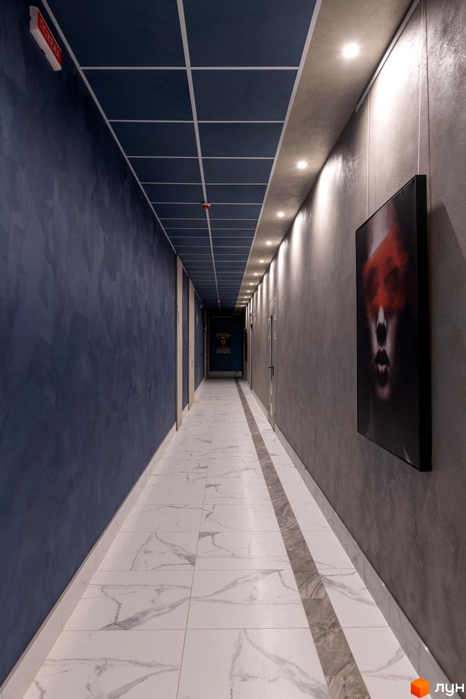 Комплекс Edelweiss House: сучасний коридор з мармуровою плиткою на підлозі та темними стінами. На стіні висить картина з портретом.