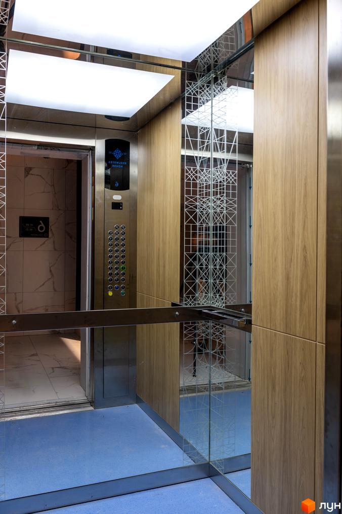 Інтер'єр ліфта в житловому комплексі Edelweiss House з дерев'яними панелями та дзеркалами. Сучасний дизайн та функціональність.