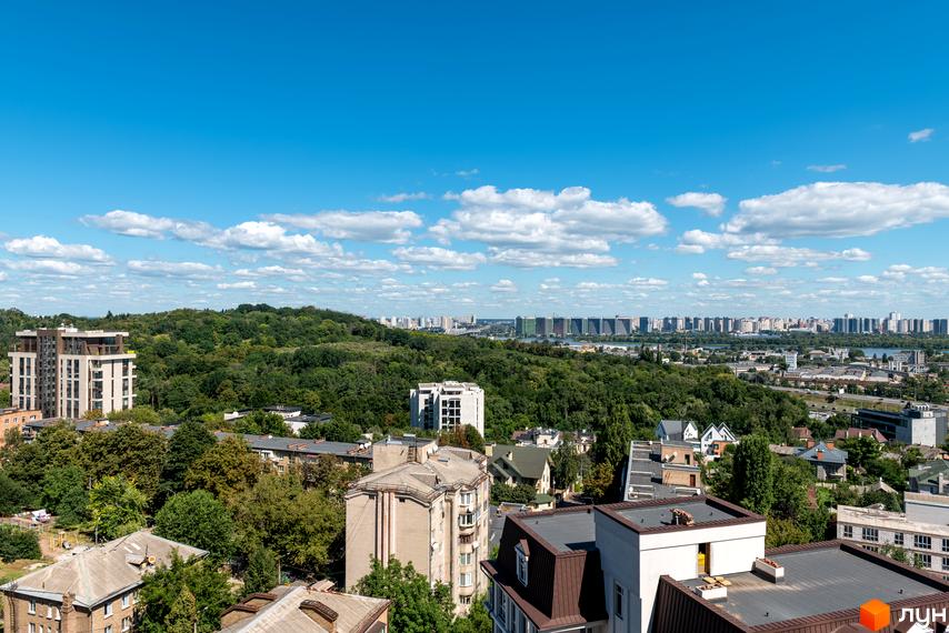 Вид на житловий комплекс Edelweiss House з висоти пташиного польоту, що демонструє його сучасну архітектуру та зелене оточення. Навколо комплексу розташовані дерева та інші будівлі, що створюють мальовничий міський пейзаж.