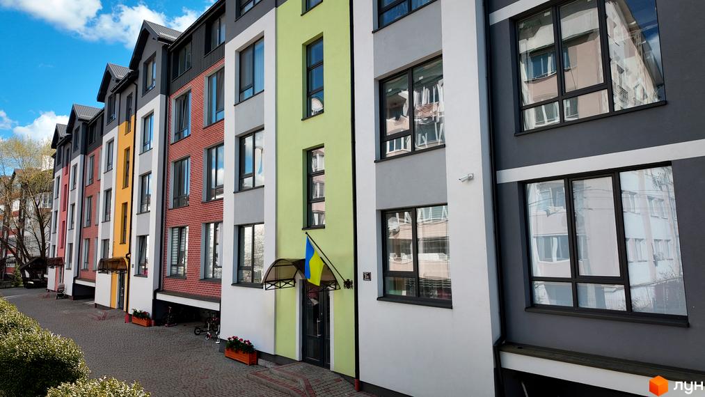 Фасад житлового комплексу Флоренція з різнокольоровими секціями та вікнами. Поруч розташована брукована доріжка та зелені насадження.