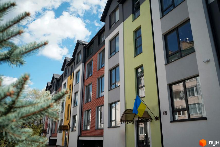 Фасад житлового комплексу Флоренція з різнокольоровими секціями та вікнами. На фоні блакитне небо з хмарами.