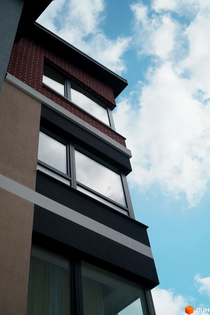 Зовнішній вигляд новобудови ЖК Вілла Венеція з цегляним фасадом та великими вікнами на тлі блакитного неба з хмарами.