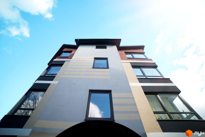 Житловий комплекс Вілла Венеція. Будинок з незвичайним фасадом та великими вікнами на фоні блакитного неба.
