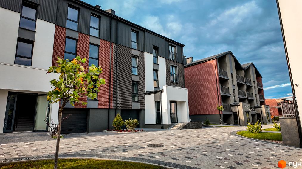 Житловий комплекс Вілла Швейцарія: фасади будинків з червоної та сірої цегли, білими вставками, балконами та прибудинковою територією з бруківки та зелених насаджень.