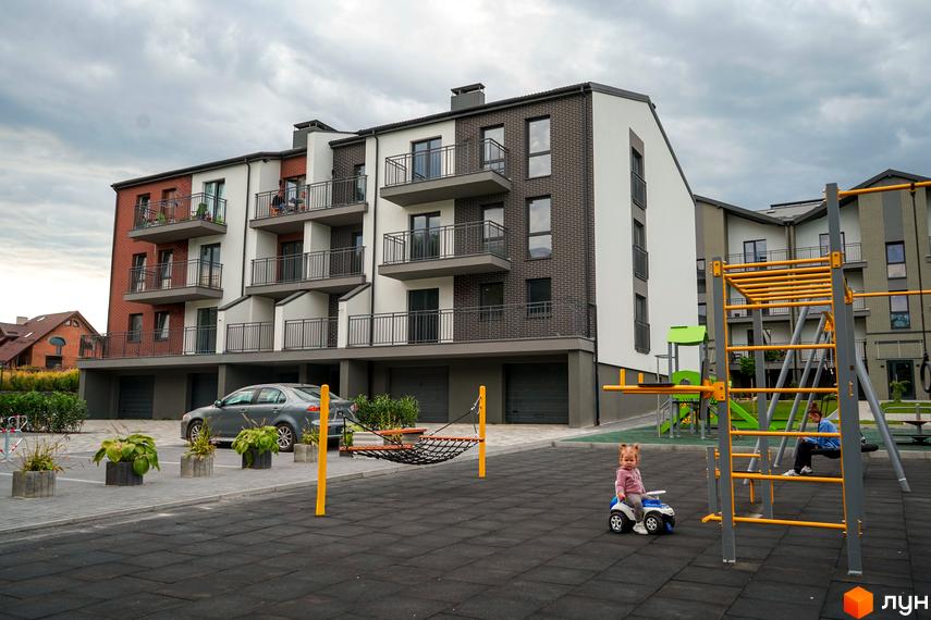 Новобудова ЖК Вілла Швейцарія з балконами та цегляним фасадом, дитячим майданчиком та парковкою.