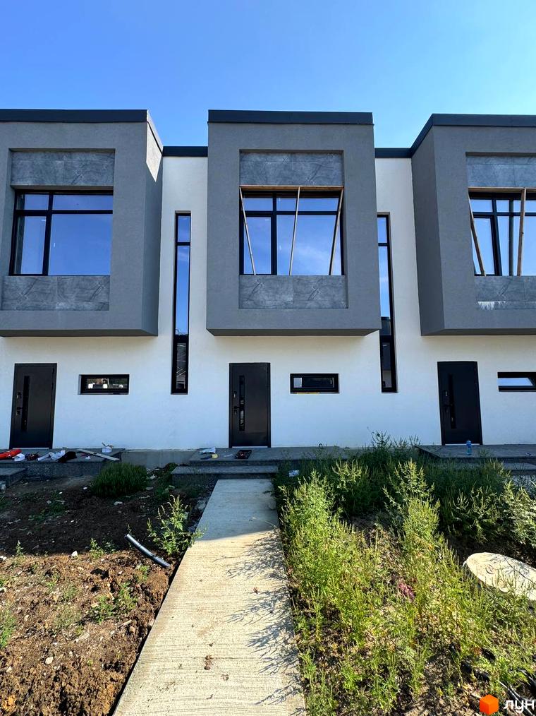 Зовнішній вигляд таунхаусів 11Dreams з сірими фасадами та великими вікнами. Прибудинкова територія з бетонною доріжкою та зеленню.