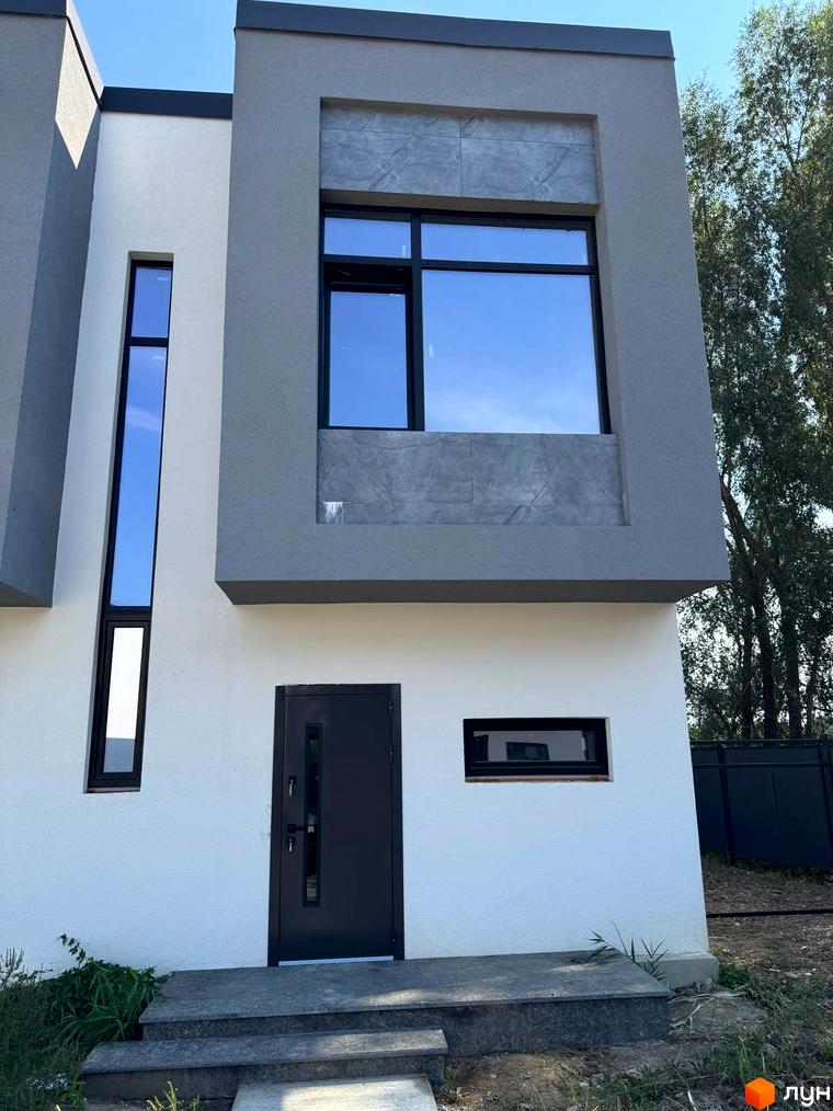 Фасад таунхаусів 11Dreams з великими вікнами та сірим оздобленням. Поруч зелена зона та паркан.