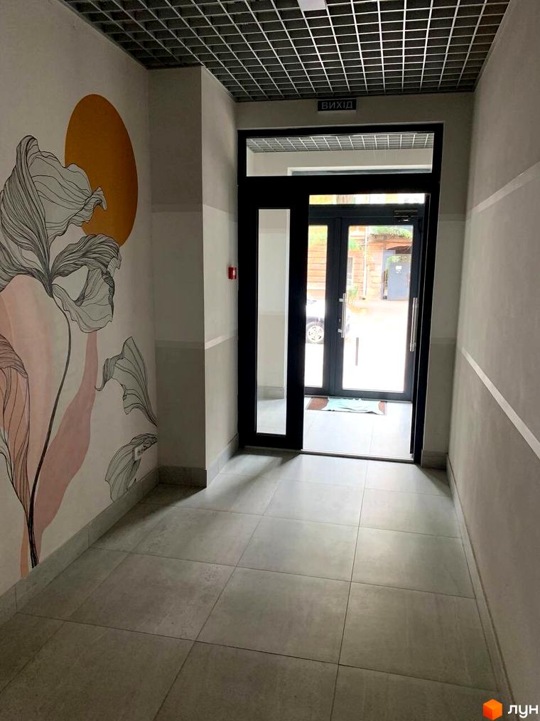 Вхідна група в житловий комплекс Будинок на Маланова з арт-об'єктом на стіні. Зовнішній вигляд новобудови та сучасний дизайн вхідної зони.