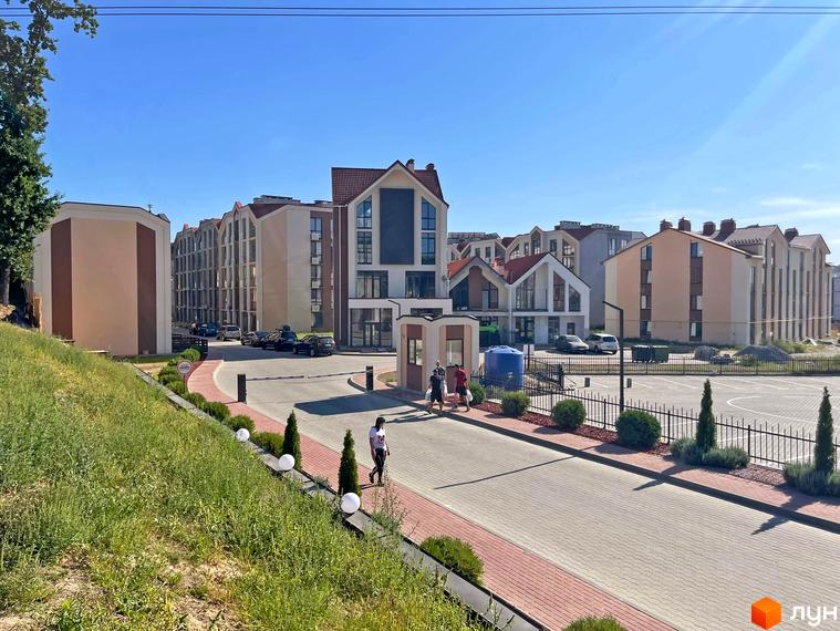 Житловий комплекс Smart Residence: фасади будинків з червоними дахами та прибудинкова територія з парканом та зеленими насадженнями. Фото новобудови.