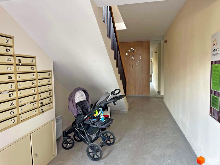 Вхідна група житлового комплексу Smart Residence з поштовими скриньками та дитячим візком. Коридор веде до сходів та виходу.