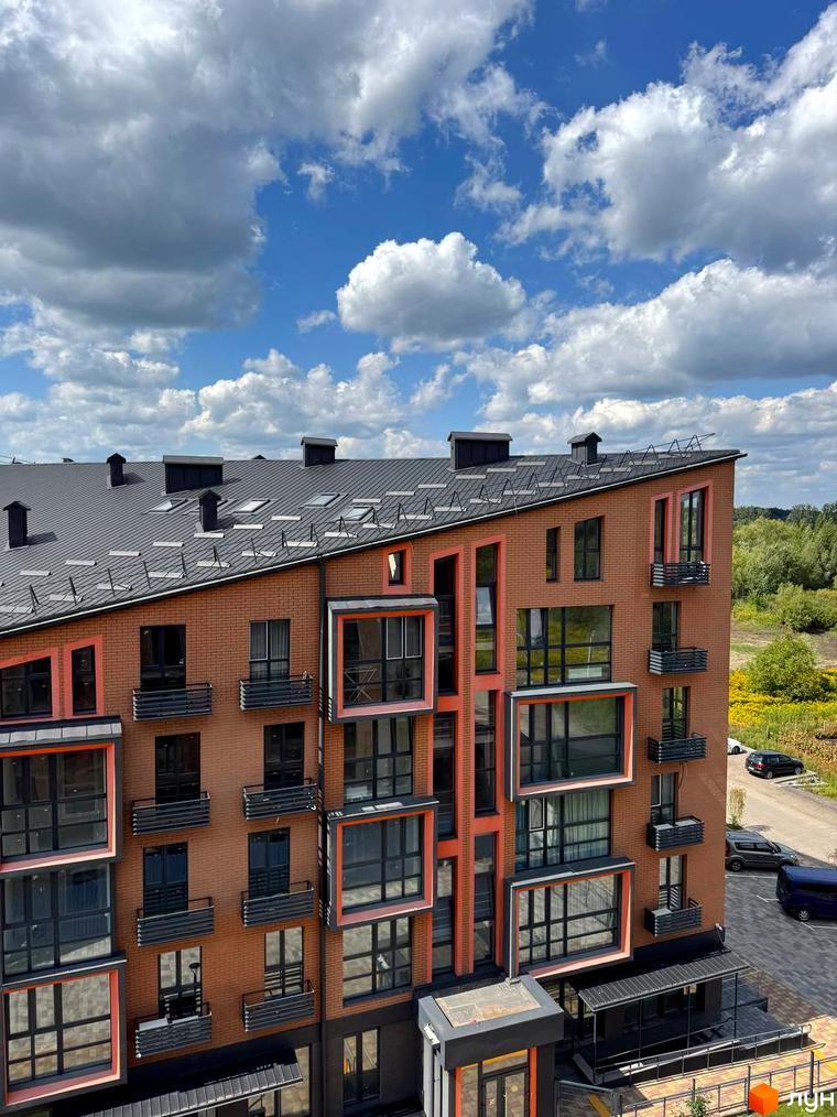 Новобудова ЖК Verba з цегляним фасадом та панорамними вікнами. Поруч дорога та зелена зона.