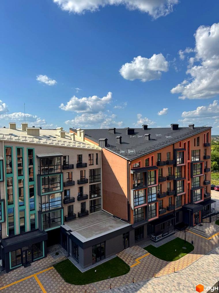 Новобудова ЖК Verba з цегляним фасадом та панорамними вікнами, прибудинкова територія з бруківкою та зеленими зонами.