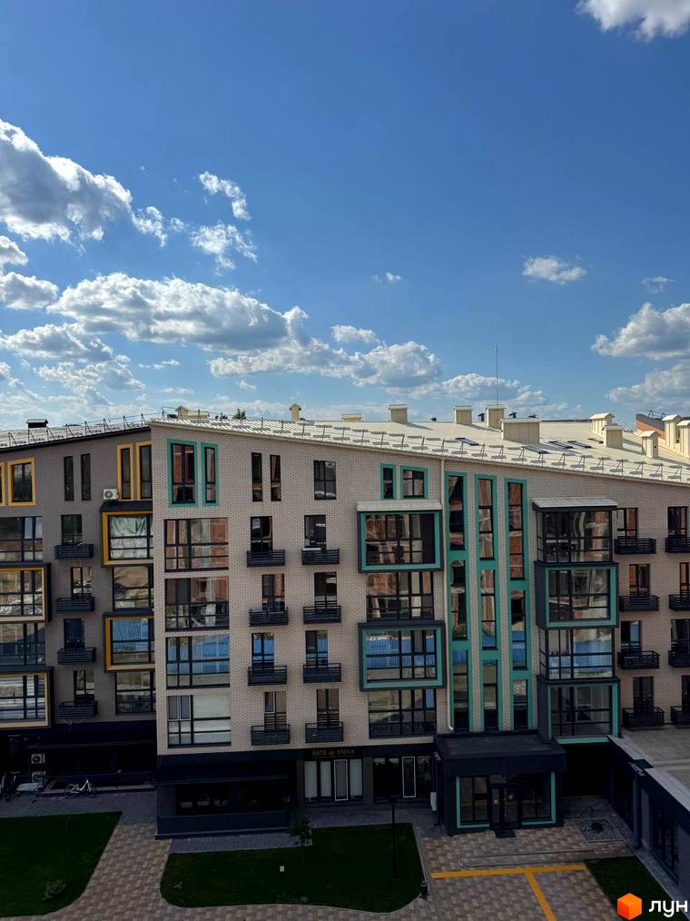 Новобудова ЖК Verba з цегляним фасадом та великими вікнами. Прибудинкова територія з зеленими зонами та доріжками.