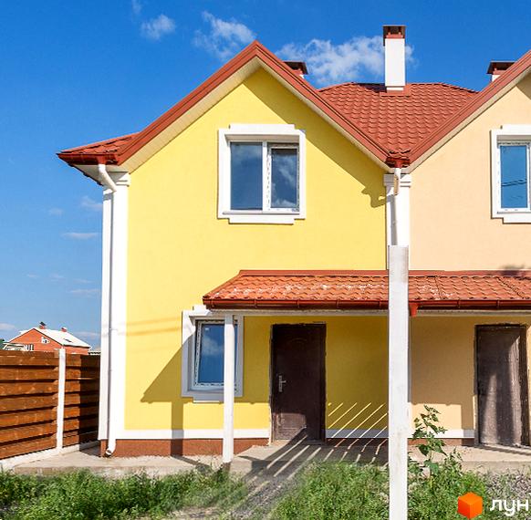 Зображення двоповерхового будинку в Котеджному містечку Garden Street з червоним дахом. Навколо будинку зелена трава.