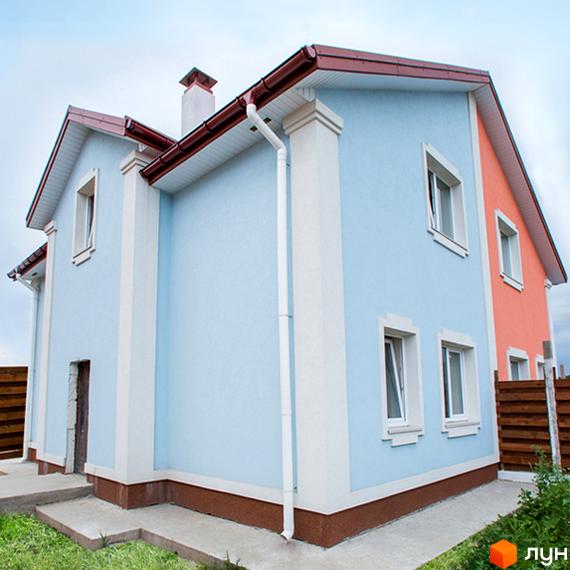 Зображення двоповерхового будинку з блакитними стінами та коричневим дахом у Котеджному містечку Garden Street. Навколо будинку зелена трава та дерев'яний паркан.