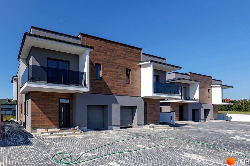 Дуплекси на Похилій: сучасні двоповерхові будинки з дерев'яним оздобленням фасаду та скляними балконами, розташовані на брукованому подвір'ї.