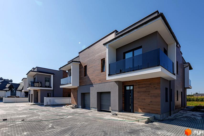 Зовнішній вигляд дуплексів на Похилій з дерев'яними фасадами та скляними балконами. Прибудинкова територія з бруківки та зелених насаджень.