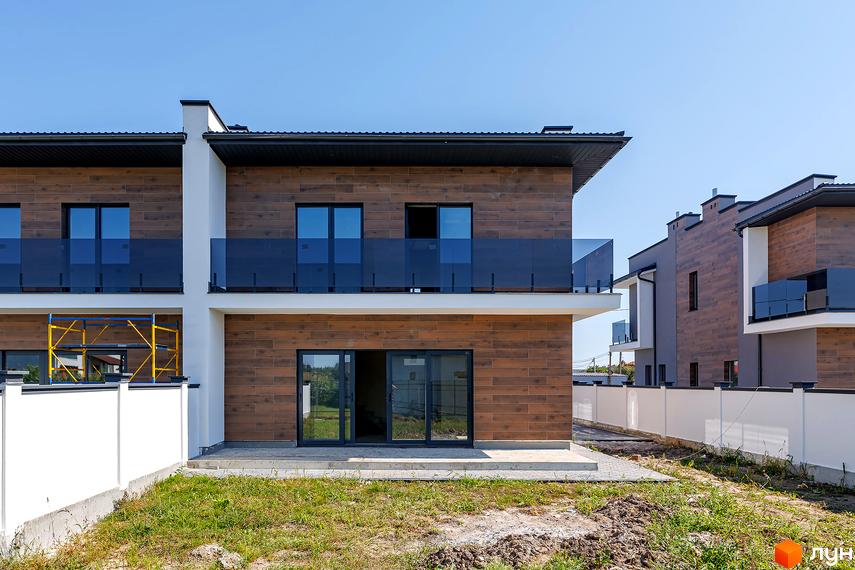 Сучасні дуплекси на Похилій з дерев'яним фасадом та скляними балконами. Навколо зелена ділянка та білий паркан.