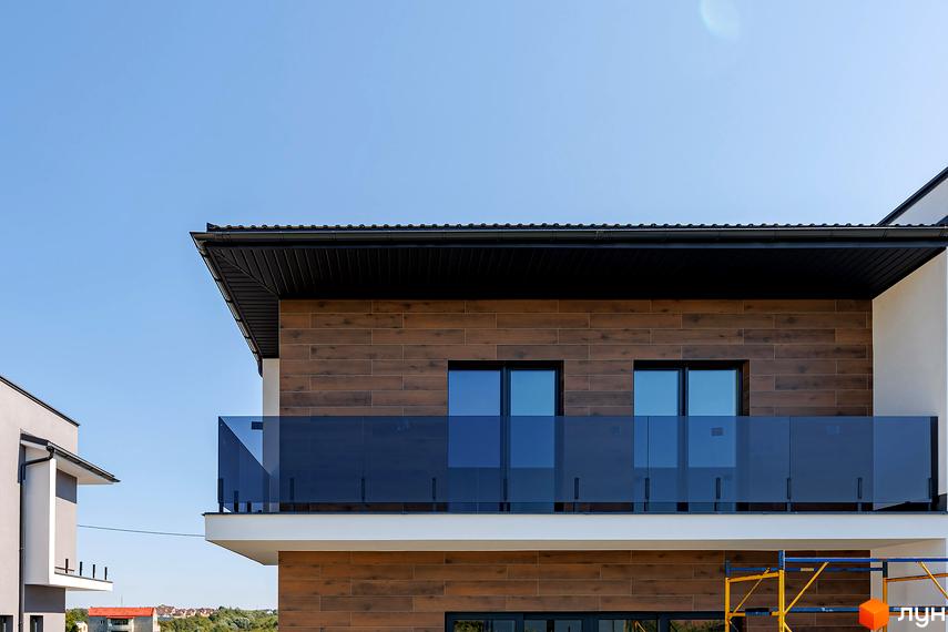 Зовнішній вигляд дуплексів на Похилій з дерев'яним фасадом та скляними балконами. Навколо видно будівлі та зелень.