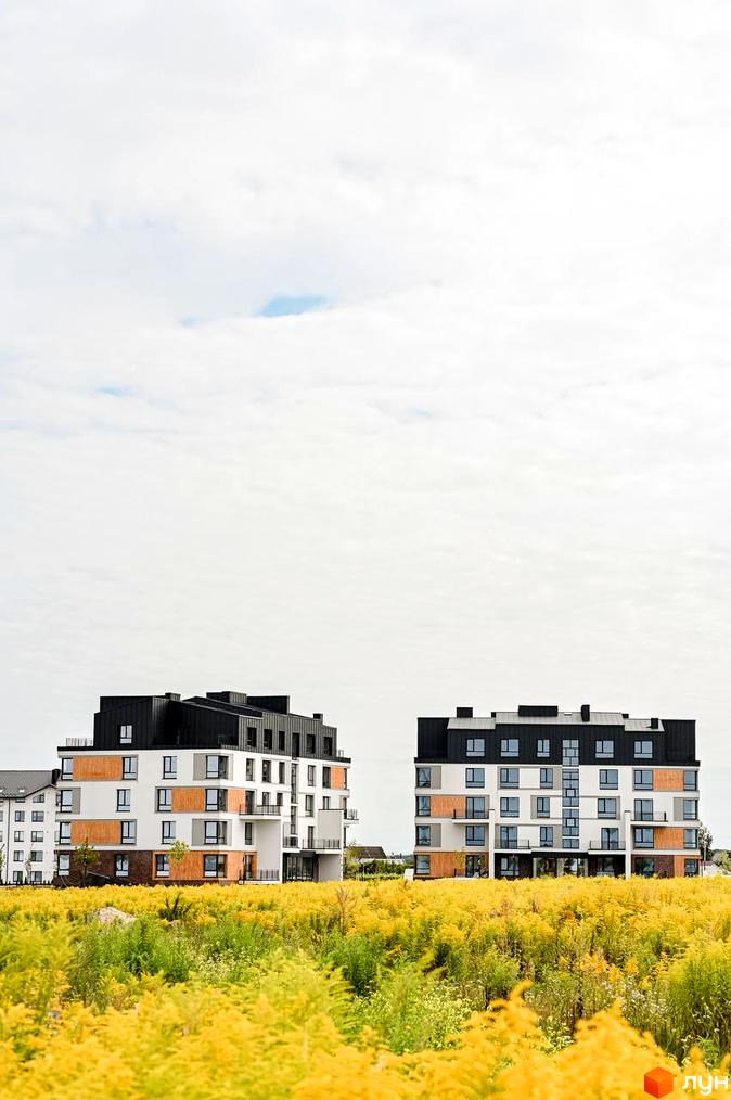 Житловий комплекс Haute Couture: білі фасади з дерев'яними вставками та чорними дахами, оточені жовтими квітами.