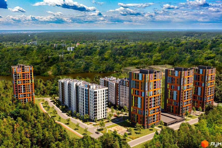Житловий комплекс Рівер Сіті з яскравими фасадами та упорядкованою прибудинковою територією, оточений лісом.