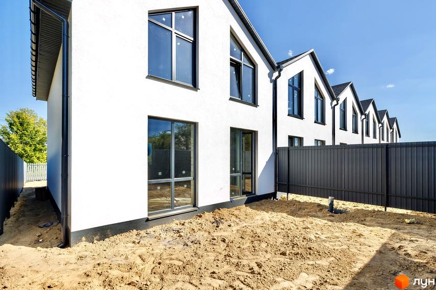 Новобудова Таунхауси Small Town з білими стінами та темними дахами, огороджена територія з піщаним покриттям.