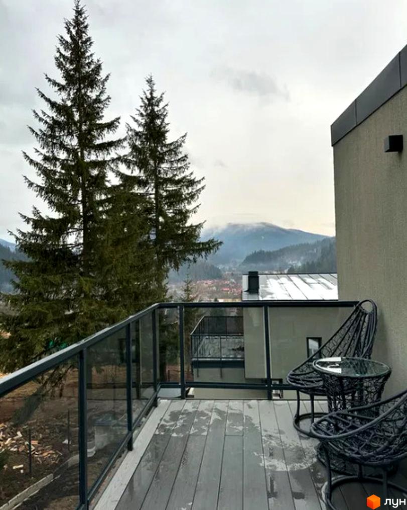 Котеджне містечко КМ Solomon Residence з балконом та видом на гори. На території комплексу розташовані ялинки та сучасні меблі для відпочинку.